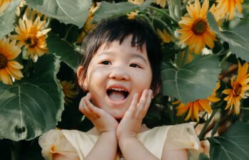 girl smiling amongst yellow flowers after waxhaw fluoride treatment