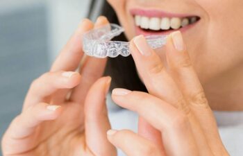 Waxhaw Invisalign patient holding tray near her mouth